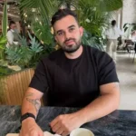 Fabio Serna sentado con un libro y un café