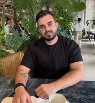 Fabio Serna sentado con un libro y un café