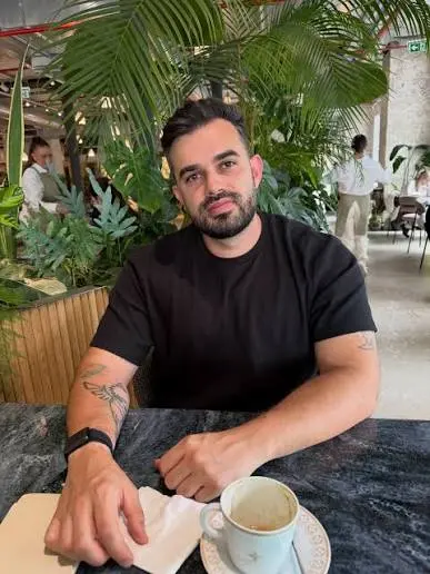 Fabio Serna sentado con un libro y un café